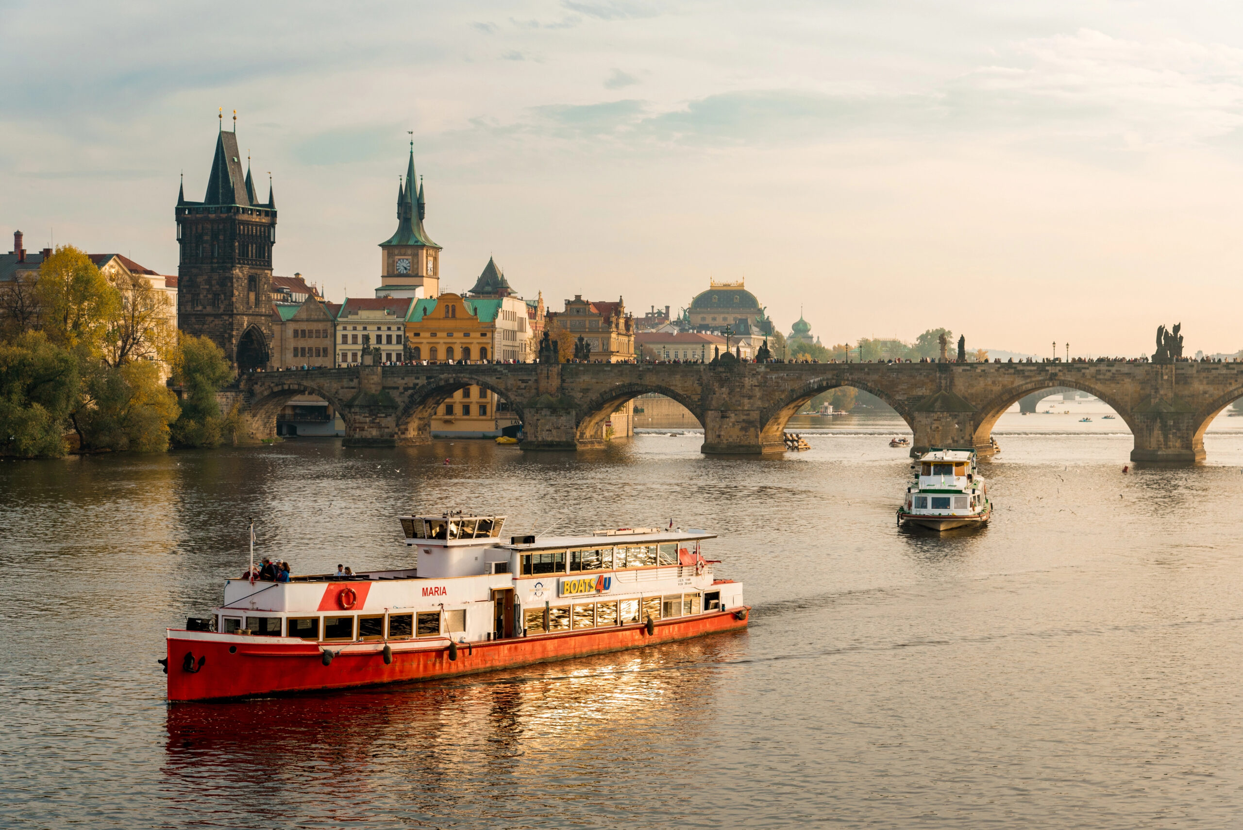 Tourist boat in Vltava river in Prague with Charles Bridge behind.